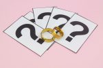 Wedding rings and question marks on pink background.