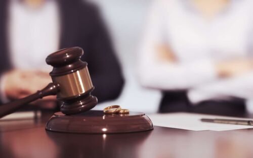 Husband and Wife Judge's Gavel and Wedding Rings with Contested and Consensual Divorce Text