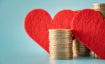 Coin stacks and heart on blue background