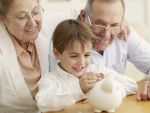 Grandparents teaching grandson to save money in a piggy bank