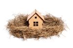 Freshly built house model placed in a bird's nest isolated on white. Family concept.