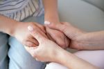 Closeup on young loving caring mother holding hands of kid girl
